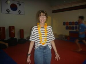 Young woman in a striped shirt and orange flower lei smiling in a gym or activity room.] , could be used as an alternative text but we need proper JSON.